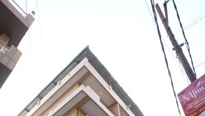 A multi-story building with balconies, large windows, and a sign indicating a restaurant. - Hotel Royale Hills (Narendranagar)
