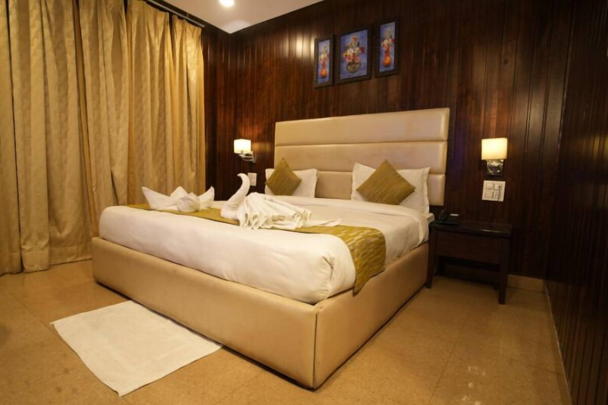A neatly made bed with a beige headboard, two bedside lamps, and a white rug on the floor.