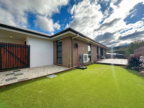 A modern house with a well-maintained lawn, a basketball hoop, and a patio area.