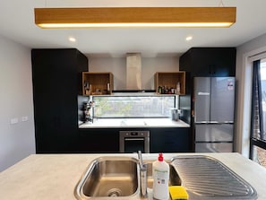 A modern kitchen with a stainless steel sink, a built-in oven, and a refrigerator.