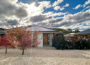 A house with a metal roof, a front door, and a gravel driveway.
