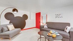 A modern living room with a grey sofa, a round coffee table with breakfast items, a large bear cutout on the wall, and a motivational quote. - 229 Suite Fantasyland - Superb apartment (Paris 02 Bourse)