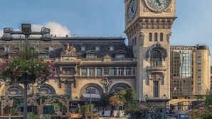 A historic building with a prominent clock tower, a cafe named "L'Erveur," and a hotel named "Cure Hotel." - 306 Suite Tigre - Superb apartment in Paris (Paris 02 Bourse)