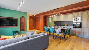 A modern living room with a grey sofa, teal chairs, and a dining area with a table and chairs. - 221 Suite Juju - Superb Apartment in Paris (Paris 13 Gobelins)