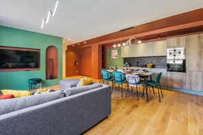 A modern living room with a sofa, dining table, chairs, and a kitchen area with cabinets and appliances. - 221 Suite Juju - Superb Apartment in Paris (Paris 13 Gobelins)
