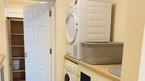 A laundry room with a washing machine, dryer, and a basket on a counter. - Brand new 2 Bedroom Home Overlooking Kenmare Bay Estuary (Kenmare)