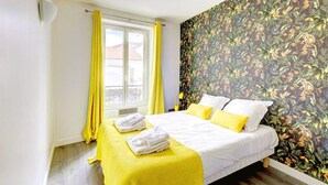 Une chambre à coucher avec un lit, des rideaux jaunes, une fenêtre et un papier peint à motifs floraux.