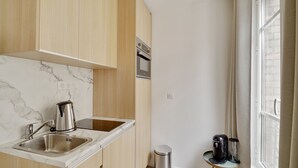 A modern kitchen with a marble countertop, stainless steel sink, and a built-in oven. - 160 Suite Eve - Superb apartment in Paris. (Paris 13 Gobelins)