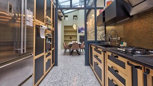 A modern kitchen with a stainless steel refrigerator, wooden cabinets, a black countertop, and a skylight above the dining area. - 334 Parisian Loft - Superb Apartment in Paris (Paris 10 Entrepôt)