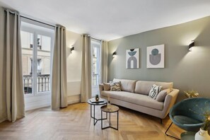 A modern living room with a sofa, two side tables, and artwork on the wall.