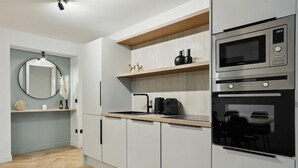 A modern kitchen with white cabinets, a wooden countertop, a built-in oven, and a microwave. - 266 Suite Montefiore Superb apartment in Paris. (Paris 02 Bourse)