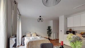 A modern bedroom with a bed, bedside table, and a dining area with a table set for two. - 340 Suite Emile - Superb apartment (Clichy)