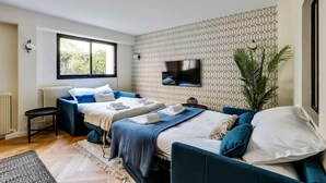 A modern bedroom with two beds, a TV mounted on the wall, and a large window. - 217 Suite Trocadero - Superb apartment in Paris (Paris 16 Passy)