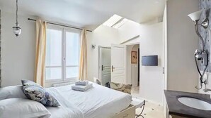 Une chambre d’hôtel comprenant un lit, une table de chevet, une salle de bain avec un lavabo et une douche.