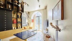 Un salon moderne avec un canapé, une table basse et une bibliothèque remplie d’objets décoratifs.