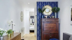 Una sala de estar moderna con un mueble de madera, un sofá y un espejo decorativo.