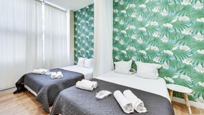 A hotel room with two beds, a large window with curtains, and a tropical wallpaper design. - 106-Suite Cece - Superb Duplex in Paris (Paris)