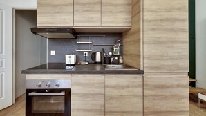 A modern kitchen with wooden cabinets, a stainless steel range, and a built-in oven. - 106-Suite Cece - Superb Duplex in Paris (Paris)