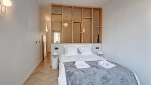 A bedroom with a large bed, wooden headboard, two bedside lamps, and a mirror. - 633 Suite Victoria - Superb apartment in Paris (Paris 02 Bourse)