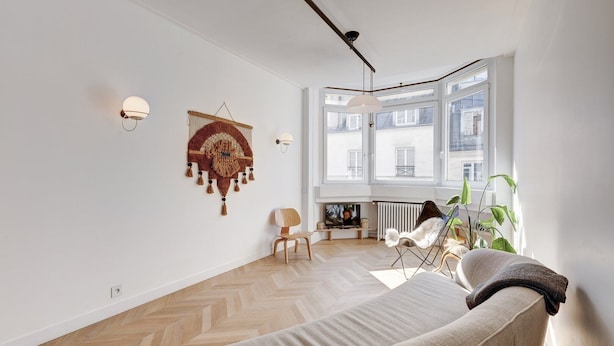 A modern living room with a sofa, a chair, a TV, and a large window with a view of buildings. - 633 Suite Victoria - Superb apartment in Paris (Paris 02 Bourse)