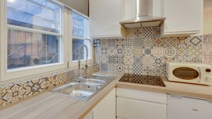 A kitchen with a double sink, a microwave, and patterned backsplash tiles. - 143 Suite La Française Superb Apartment in Paris (Paris 19 Buttes-Chaumont)