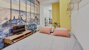 A bedroom with a bed, a wooden bench, a TV, and a cityscape mural on the wall. - 143 Suite La Française Superb Apartment in Paris (Paris 19 Buttes-Chaumont)