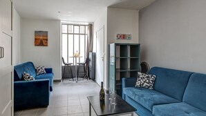 Una sala de estar moderna con dos sofás azules, una mesita con vasos y una estantería.