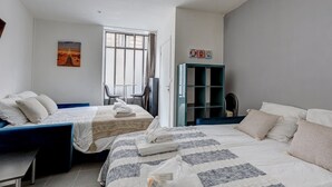 Un dormitorio con dos camas, un escritorio, una silla, un armario y una ventana.
