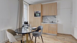 Eine kompakte Küche mit Holzschränken, einem eingebauten Backofen und einer Marmor-Spritzschutzwand.