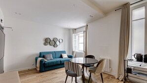 Ein modernes Wohnzimmer mit einem blauen Sofa, einem runden Tisch und gemusterten Sesseln.