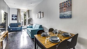 Ein modernes Wohnzimmer mit Essbereich, mit einem Holztisch, gedeckt für zwei Personen, einem blauen Sofa und einem großen abstrakten Gemälde an der Wand.