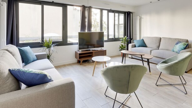 A modern living room with a sofa, two armchairs, a coffee table, and a TV. - 173 Suite Eiffel - Superb apartment in Paris. (Paris 15 Vaugirard)