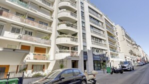 A multi-story residential building with balconies, a ground-level entrance, and parked vehicles. - 173 Suite Eiffel - Superb apartment in Paris. (Paris 15 Vaugirard)