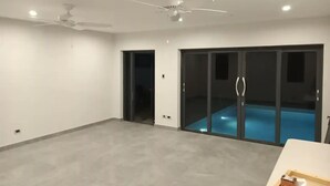A spacious room with a large sliding glass door leading to a pool area. - Queen Room with Pool View (Oistins)