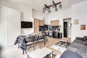 A compact living space with a dining area, kitchenette, and a sofa.