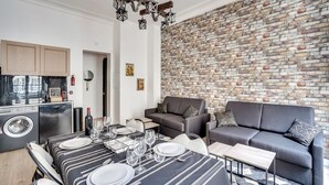 Un espacio de estar moderno con comedor, un sofá gris y una pared de ladrillo.