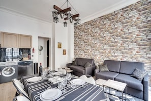 A modern living space with a dining area, sofa, and kitchen.
