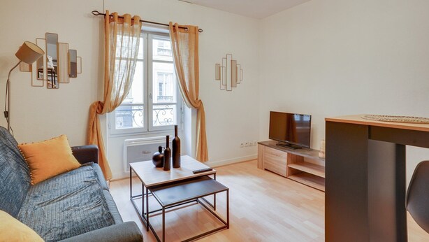 A modern living room with a sofa, coffee table, TV, and a window with curtains. - 246 Suite Naples Superb apartment in Paris (Paris 17 Batignolles-Monceau)