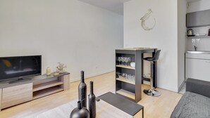 A modern living room with a flat-screen TV, wooden furniture, a black coffee table, and a minimalist design. - 246 Suite Naples Superb apartment in Paris (Paris 17 Batignolles-Monceau)