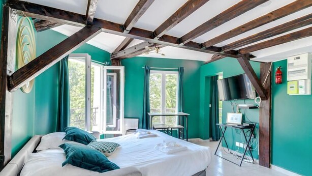 Ein Schlafzimmer mit einem Bett, einem Schreibtisch und einem Stuhl. Ein Fenster und eine Tür sind vorhanden.