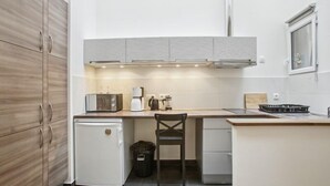 Una cocina compacta con refrigerador integrado, cafetera y un lavamanos pequeño.