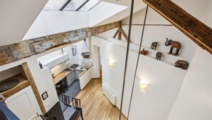 Una cocina moderna con tragaluz, vigas de madera y un comedor con sillas.