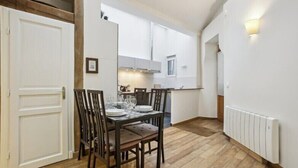 Cocina compacta con comedor, piso de madera y radiador blanco.