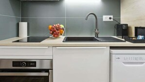 Une cuisine moderne avec des meubles de couleur bois clair, un lave-vaisselle en acier inoxydable et un four encastré.