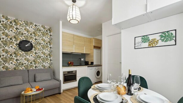 Un appartement moderne comprenant un coin repas, une kitchenette et un salon avec un canapé et une petite table d’appoint.