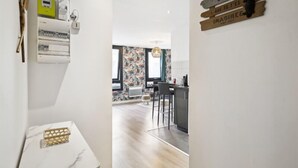 Una cuina moderna amb taulell de marbre, una zona de dinar amb un tamboret i una paret decorativa amb indicadors de fusta.