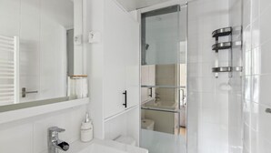 A modern bathroom with a glass shower enclosure, a white sink, and a mirror above the sink. - 821 Suite Licorne - Superb apartment (Les Lilas)