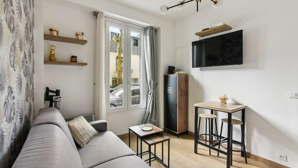 A modern living room with a sofa, a small table, a TV mounted on the wall, and a cabinet. - 821 Suite Licorne - Superb apartment (Les Lilas)