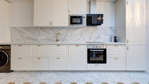 A modern kitchen with white cabinetry, a built-in microwave, a stainless steel oven, and a marble backsplash. - 348 Ponthieu - Superb apartment in Paris (Paris 08 Élysée)