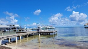 Ein Yachthafen mit vertäuten Booten, eine Pier, die sich ins Wasser erstreckt, und ein kleines Gebäude auf der linken Seite.
